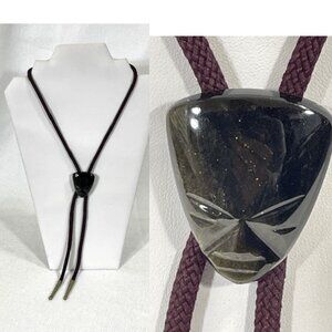 Carved stone face bolo tie with dark brown cord and brown/black face.